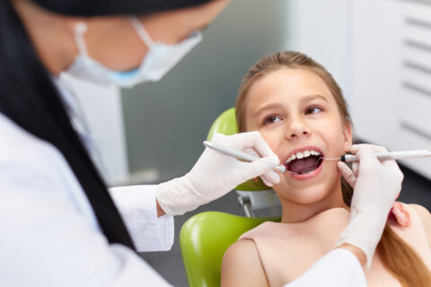 Teeth checkup at dentist's office. Dentist examining girls teeth in the dentists chair